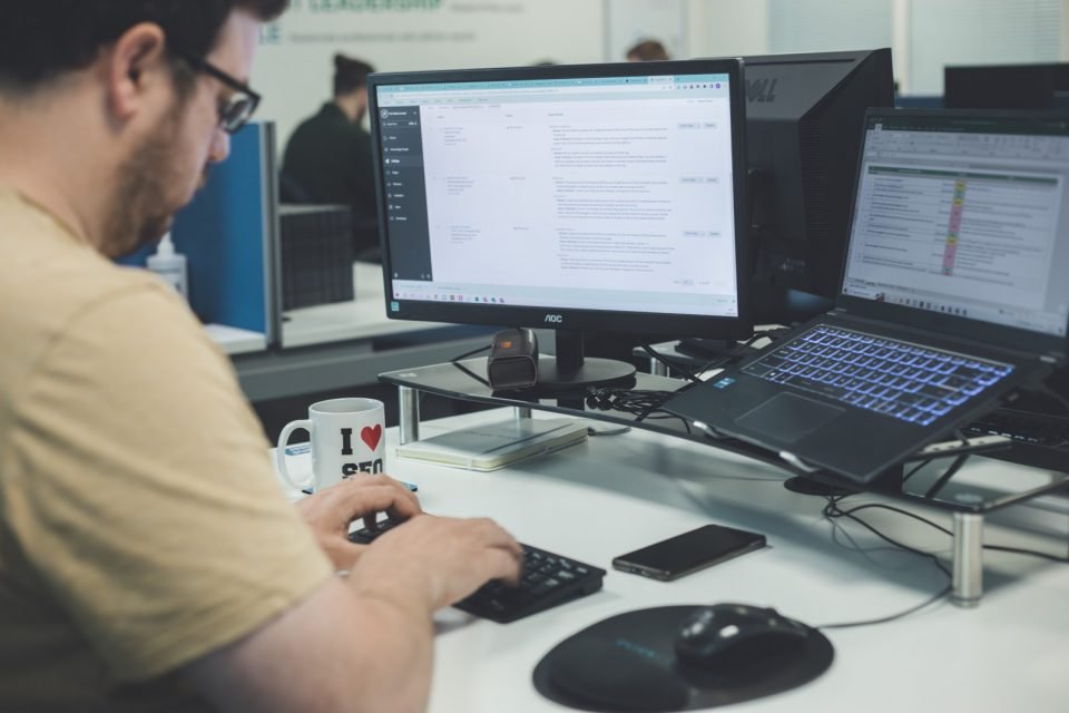 Person researching keywords/trends on multiple screens.