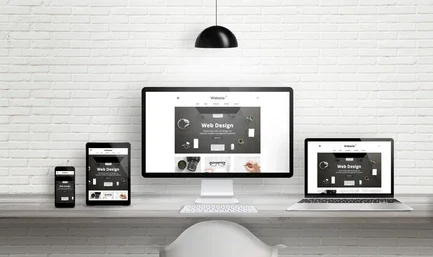 Illustration of a modern, clean business website displayed perfectly across a laptop, a tablet, and a mobile phone screen.