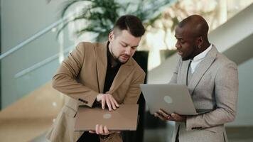 2 South African man collaborating on laptops in a modern office.